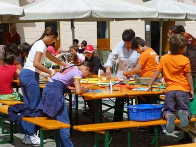 Febbrile attività di ragazze e ragazzi ai tavoli della fabbrica degli smilzi